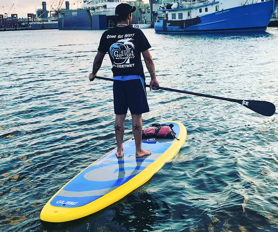 Guy in black shirt and shorts paddle boarding